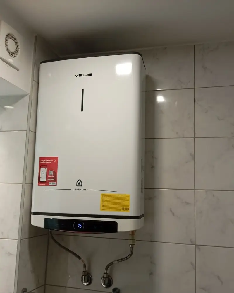 Ariston Velis bojler ugrađen iznad cijevi u kupatilu s bijelim pločicama